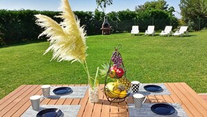 A wooden deck with a table set for a meal, surrounded by a lush green lawn and a barbecue grill in the background. - Stylish Casa Lavanda with private pool and garden in Vrsar (Vrsar)
