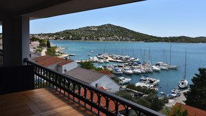 A balcony with a view of a marina with boats, a hill in the background, and buildings along the shore. - Villa Pina Tisno **** Penthouse apartment by the sea 140 m2 in Tisno-Dalmatia (Tisno)