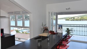 A modern kitchen with a large window overlooking a marina and a balcony with red bar stools. - Villa Pina Tisno **** Penthouse apartment by the sea 140 m2 in Tisno-Dalmatia (Tisno)