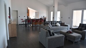 A spacious living area with grey sofas, a coffee table, and a kitchen in the background. - Villa Pina Tisno **** Penthouse apartment by the sea 140 m2 in Tisno-Dalmatia (Tisno)