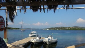 A view from a boat docked at a marina with boats and a sailboat in the background. - Villa Pina Tisno **** Penthouse apartment by the sea 140 m2 in Tisno-Dalmatia (Tisno)