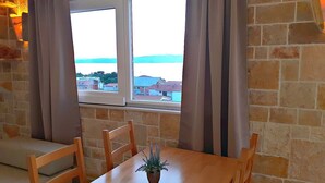 A room with a wooden table, chairs, a potted plant, and a window with curtains.
