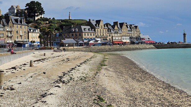 A coastal town with historic buildings, a promenade, and a lighthouse.