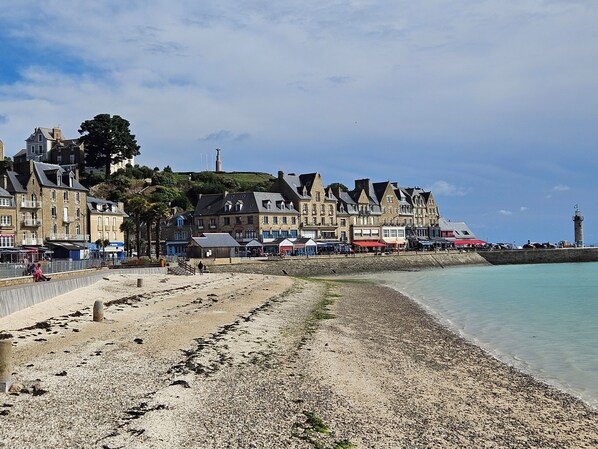 Une ville côtière dotée de bâtiments historiques, d’une promenade et d’un phare.