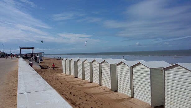 Une plage bordée de cabanes de plage et surmontée d’une tour de surveillance des sauveteurs.