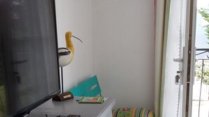 Un petit espace de vie comprenant un téléviseur, un bureau, une chaise et un canapé coloré.