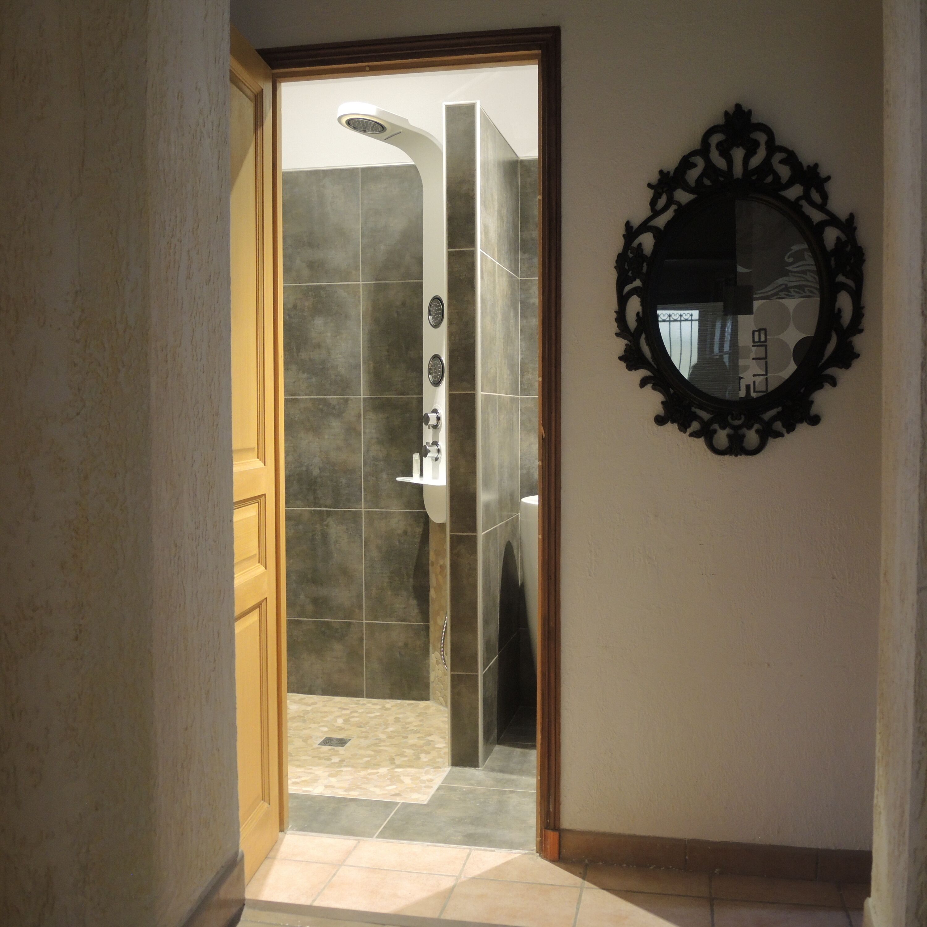 Une salle de bain avec une douche, un lavabo et un miroir au mur.
