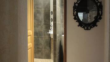 Une salle de bain avec une douche, un lavabo et un miroir au mur.