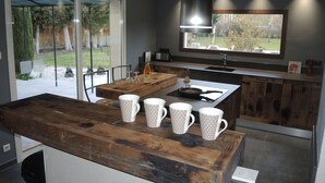 Une cuisine moderne avec un îlot central en bois, une grande fenêtre et une vue sur l’extérieur.