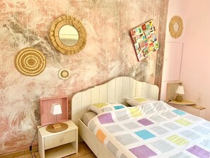 Relax in this charming bedroom with a quilted bedspread, bedside table, and decorative mirrors.