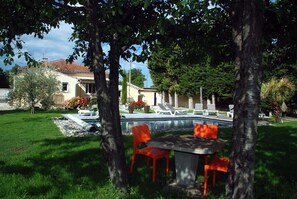 Relax by the serene pool surrounded by lush greenery and trees, perfect for a leisurely day.