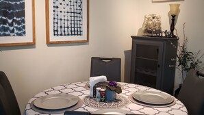 A dining area with a round table, chairs, and a cabinet with a sign above it.