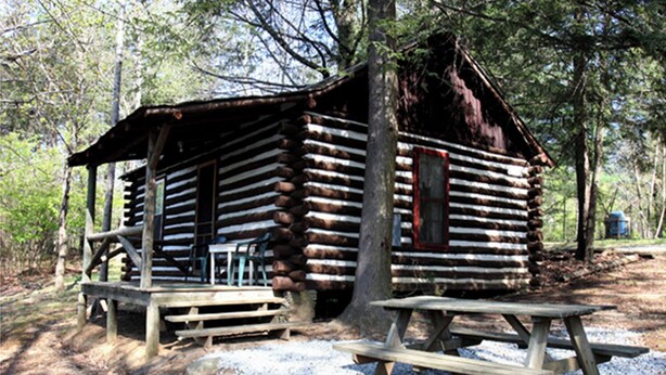 A rustic log cabin with a porch and picnic table. - Historic one bedroom log cabin (Lake Lure)