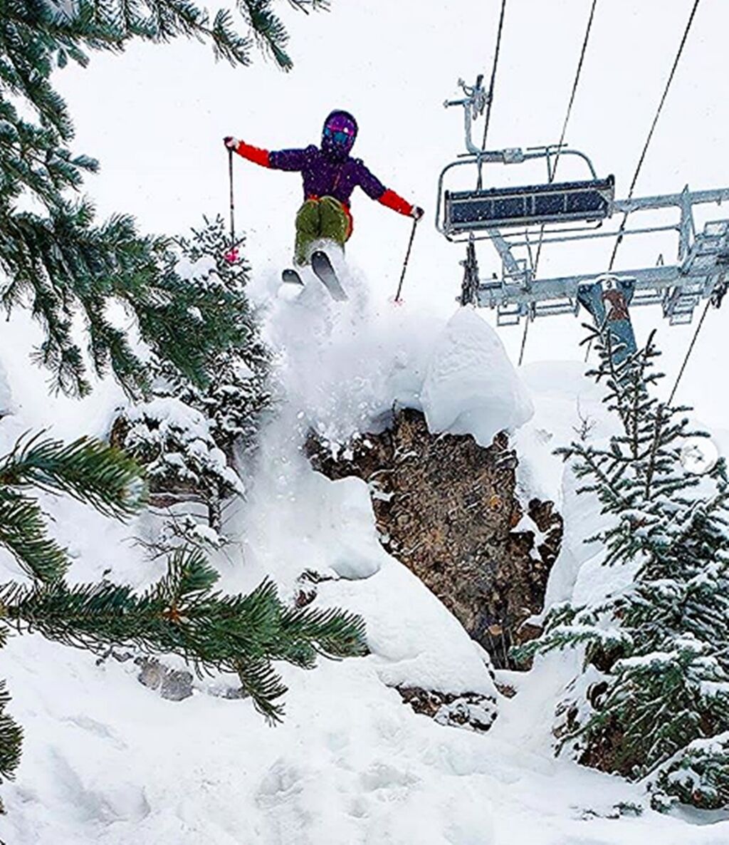A person skiing on a snowy slope with a ski lift in the background.