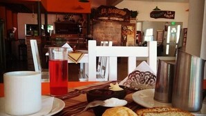 A breakfast setting with a table set for two, including plates, a cup, a teapot, and bread. - Sol y Luna (Los Molles)