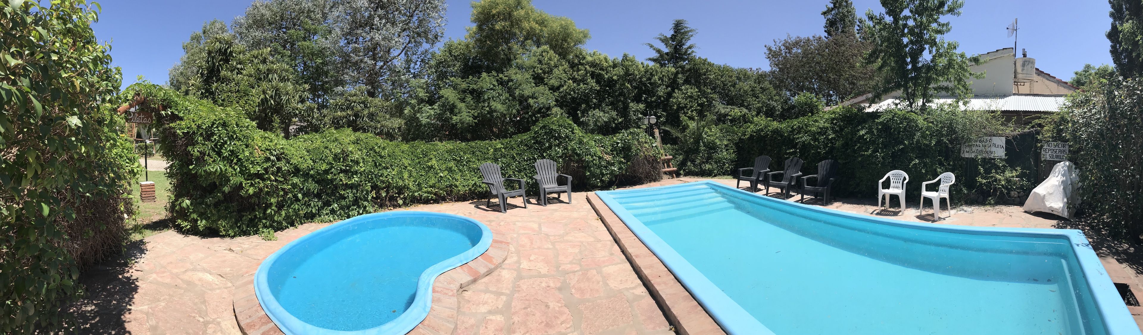 Piscina con dos carriles, rodeada de abundante vegetación y senderos de piedra.