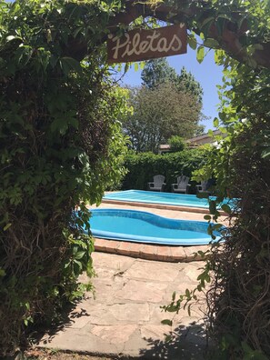 Un área de piscina con un cartel que dice "Piletas" y un sendero de piedra que conduce a ella.