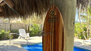 A wooden surfboard-shaped sign with the text "B on the Beach" and a question "What could be BETTER than this?" attached to a wooden post by a pool area. - Private Beach House Oasis! Heated Pool, Tiki hut, Ocean few houses away (Cape Canaveral)