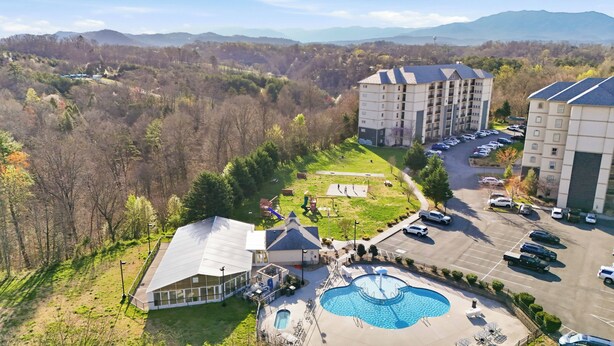 Ein Hotel mit Schwimmbad, Parkplatz und Blick auf den umliegenden Wald und die Berge.