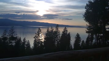 Una vista serena de un lago tranquilo, montañas distantes y un bosque de árboles altos.