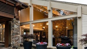 A modern building with large windows, stone pillars, and outdoor potted plants.