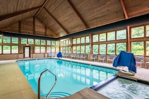An indoor swimming pool with wooden beams, clear windows, and lounge chairs. - Lake Lure North Carolina | Family Lake Retreat | Pool + Lake | 2BR (Lake Lure)