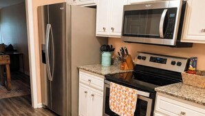 A kitchen with white cabinets, stainless steel appliances, and a patterned rug.
