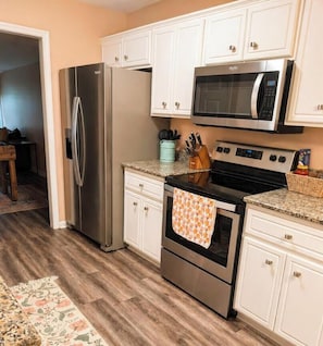 A kitchen with white cabinets, stainless steel appliances, and a patterned rug. - The Peach Club - Across from the Augusta National (Augusta)
