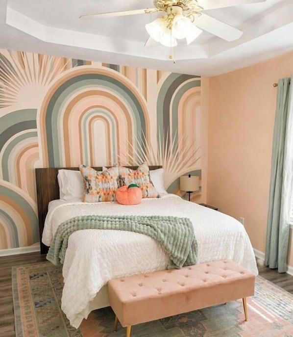 A bedroom with a bed, a bench, a ceiling fan, and a wall with a geometric pattern.