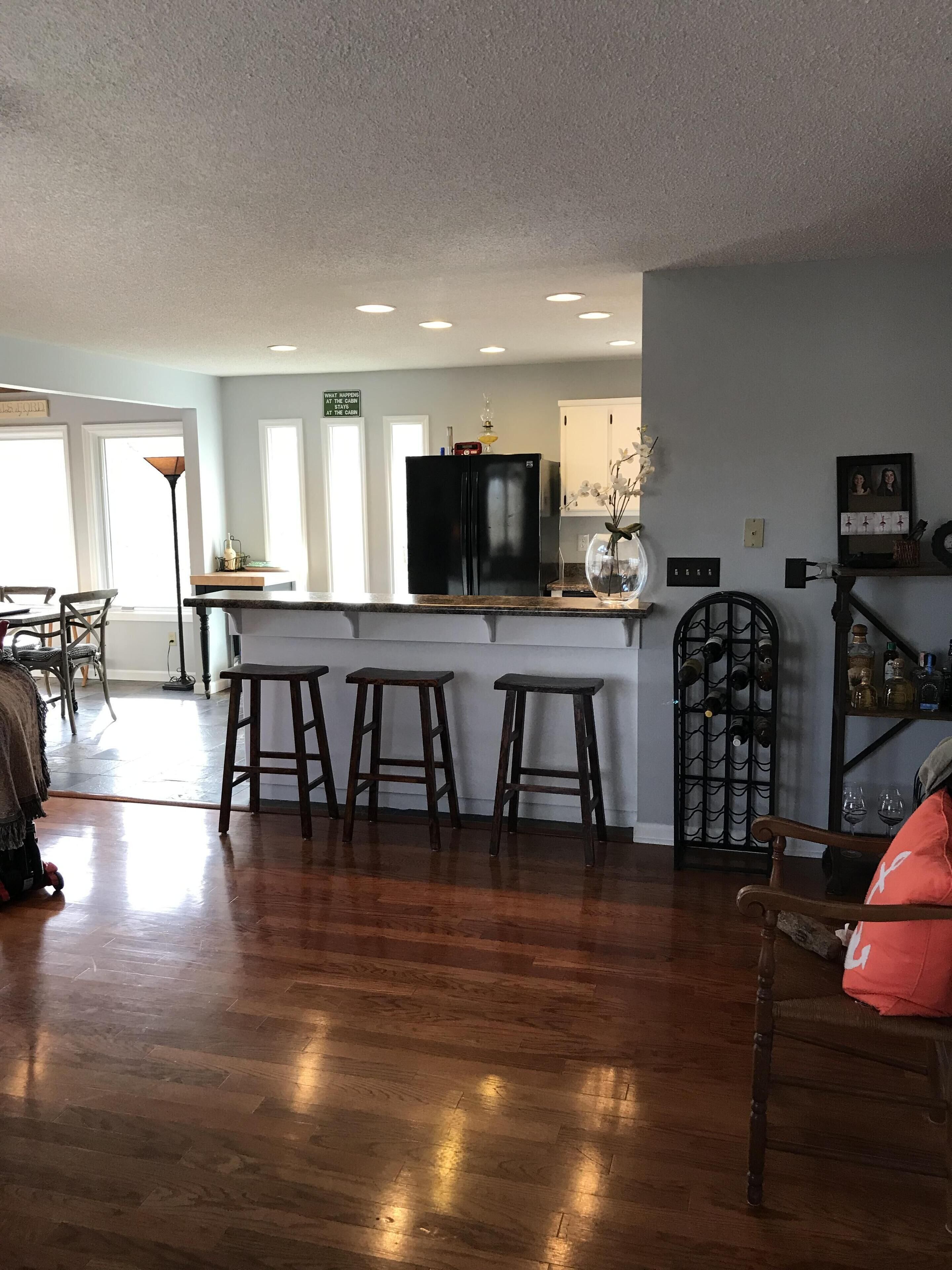 A spacious kitchen with a central island, bar stools, and a wine rack.