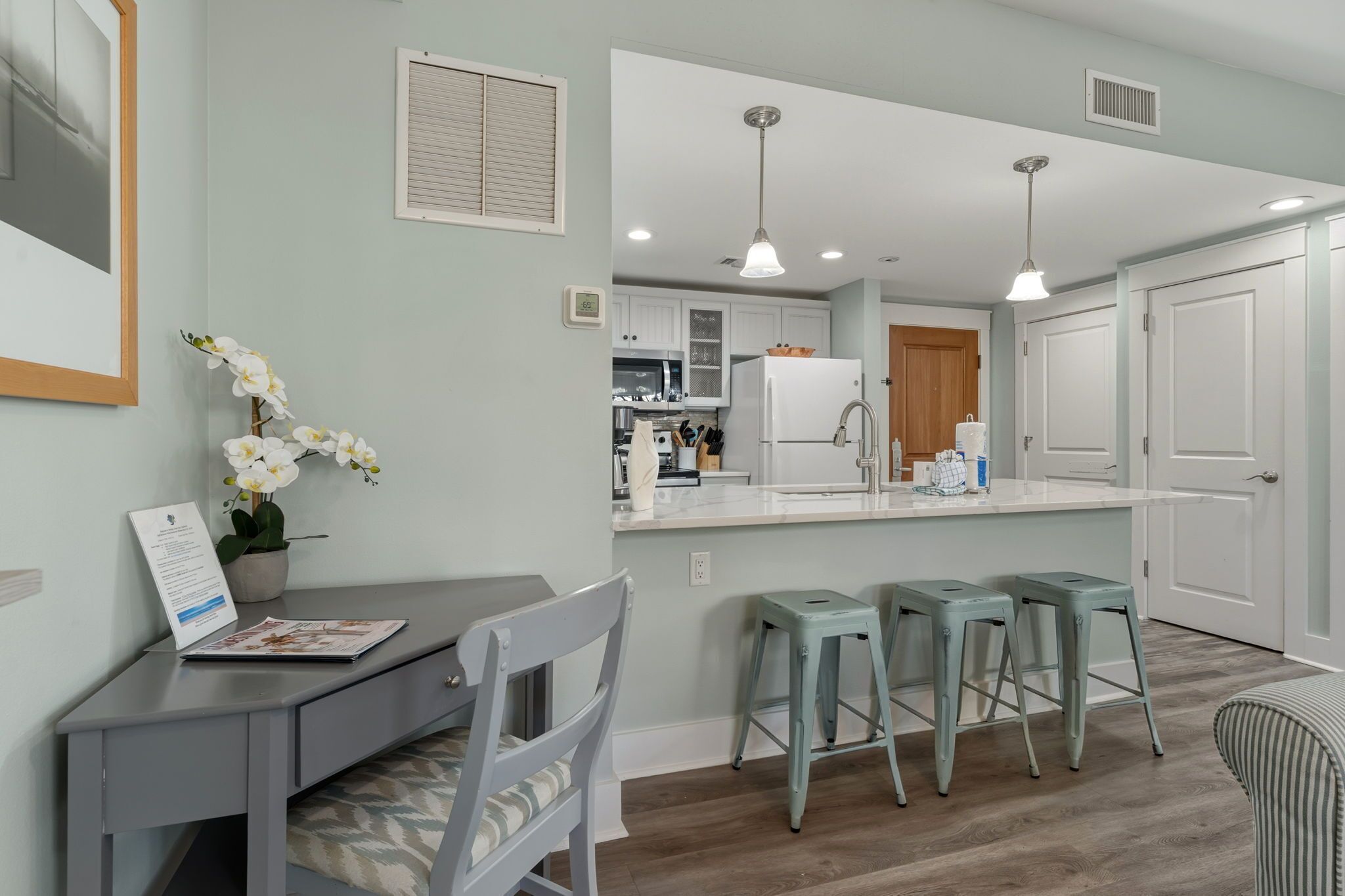 A modern kitchen with white cabinets, a central island, and bar stools.