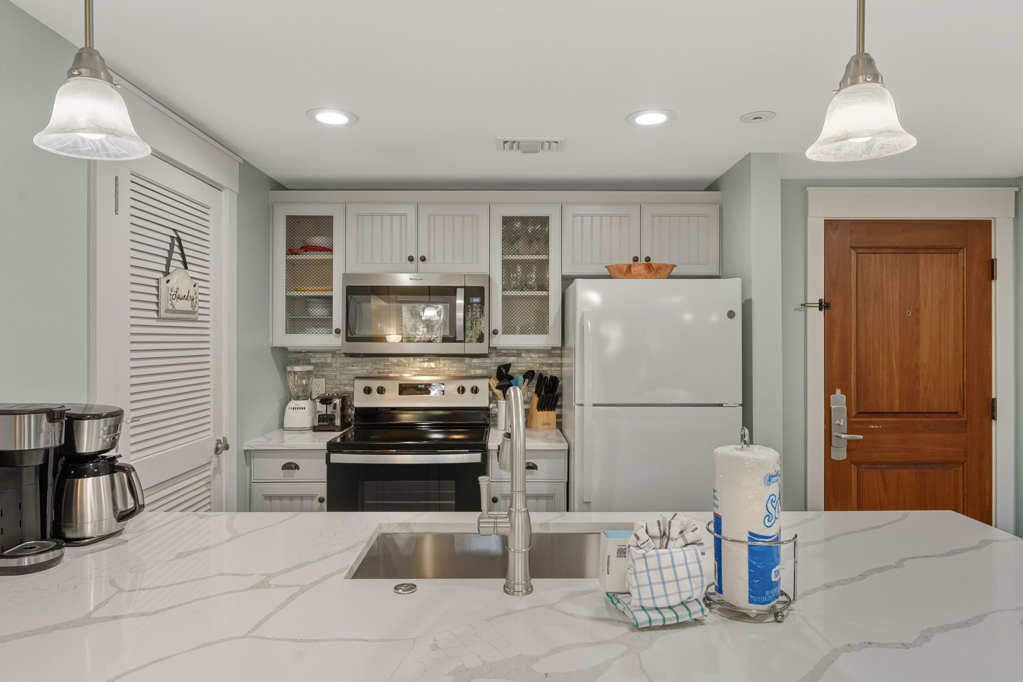 A kitchen with white cabinets, a refrigerator, a stove, and a coffee maker.