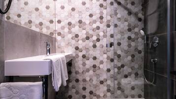 A modern bathroom with a glass shower enclosure, a white sink, and a hexagonal patterned wall.