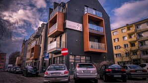 Een modern gebouw met balkons, een verboden toegang-bord en geparkeerde auto's.