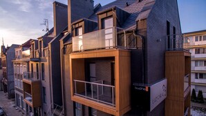 Een modern gebouw met een gevel van baksteen en hout, voorzien van balkons en een bord met 'budnex'.