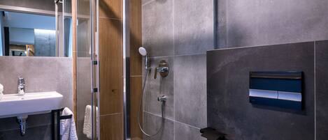 Un baño moderno con cabina de ducha de vidrio, inodoro blanco y lavabo con espejo.