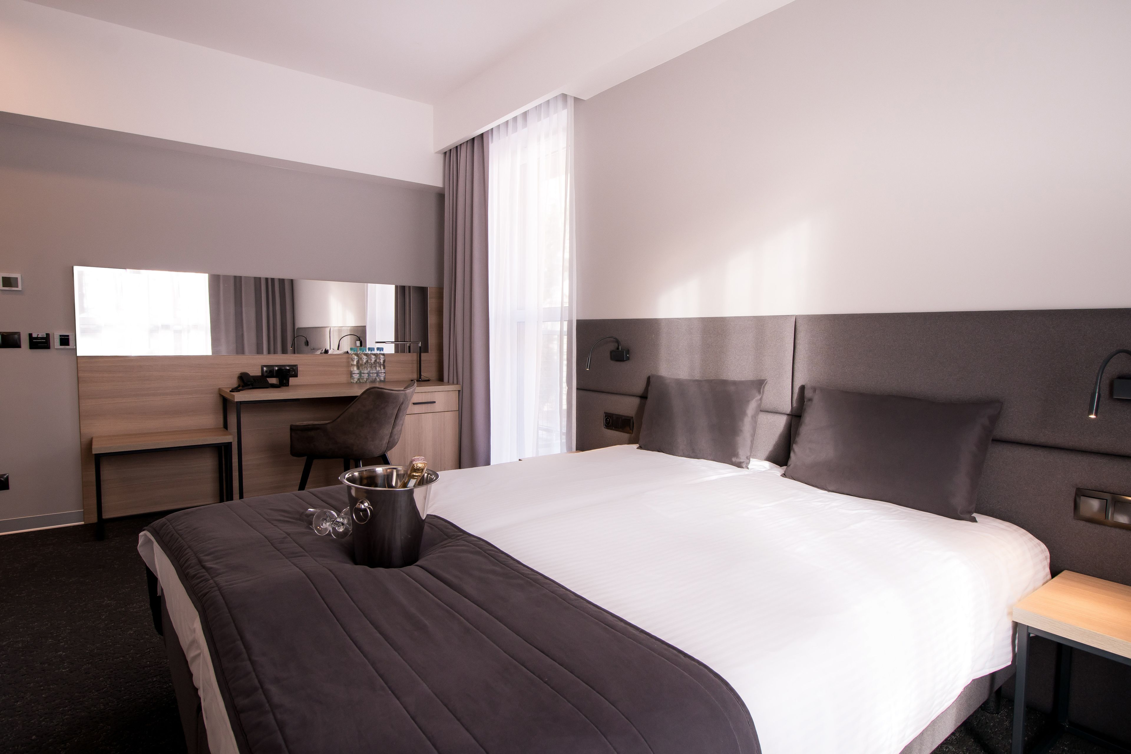 Una habitación de hotel moderna con una cama grande, un escritorio, una silla y una mesita.