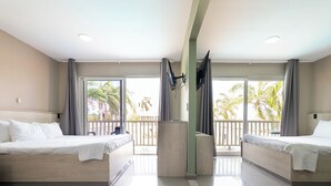 A hotel room with two beds, a TV, and a balcony with palm trees. - Delynne Boutique Hotel (Willemstad)