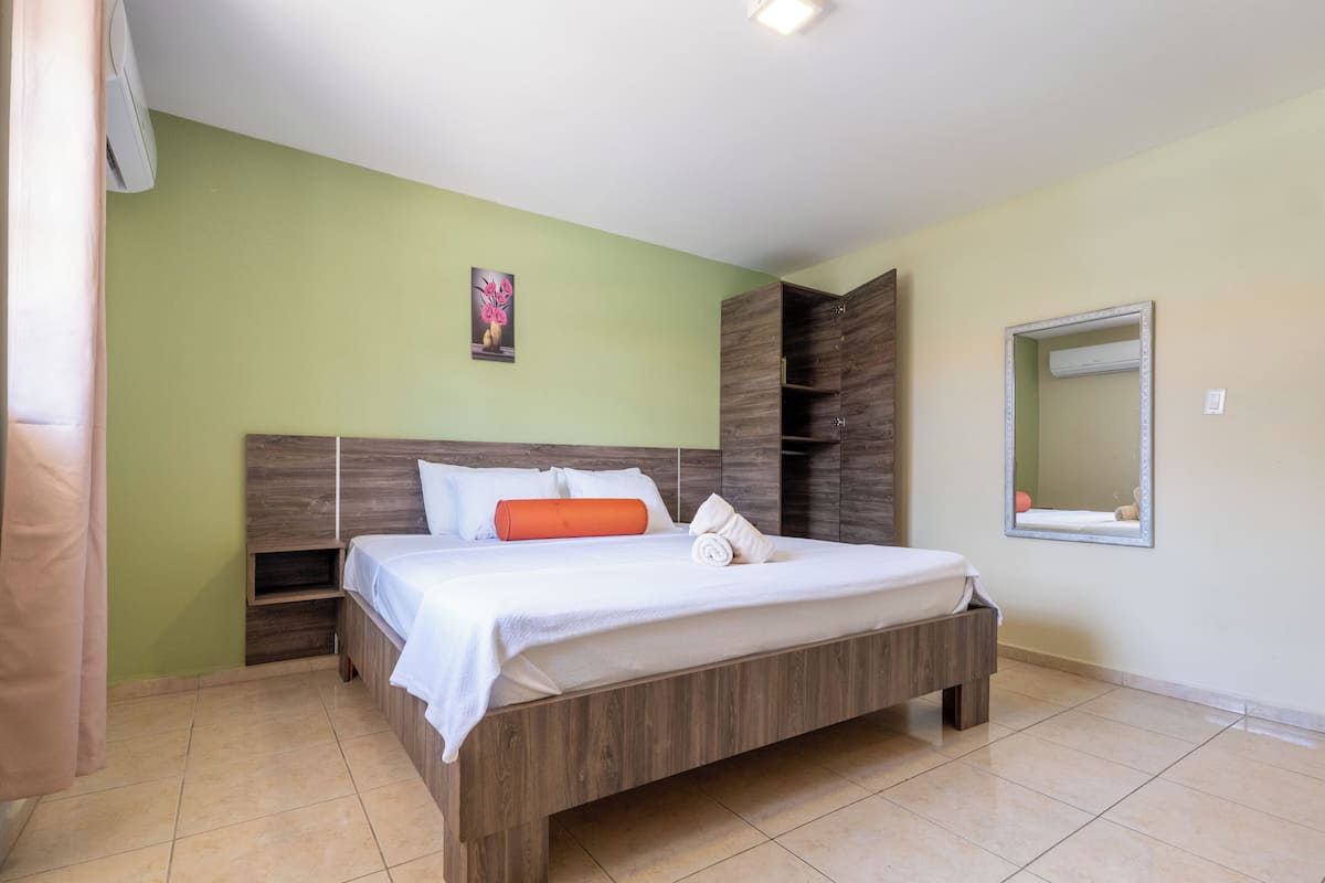 Camera da letto con un letto, un comodino, uno specchio e un condizionatore d'aria a muro.