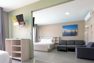 Una habitación de hotel con una cama, un sofá, un televisor montado en la pared y un cuadro.
