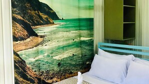 Ein Hotelzimmer mit einem Bett, einem großen Fenster mit Blick auf eine Küstenlandschaft und einem Kleiderschrank.