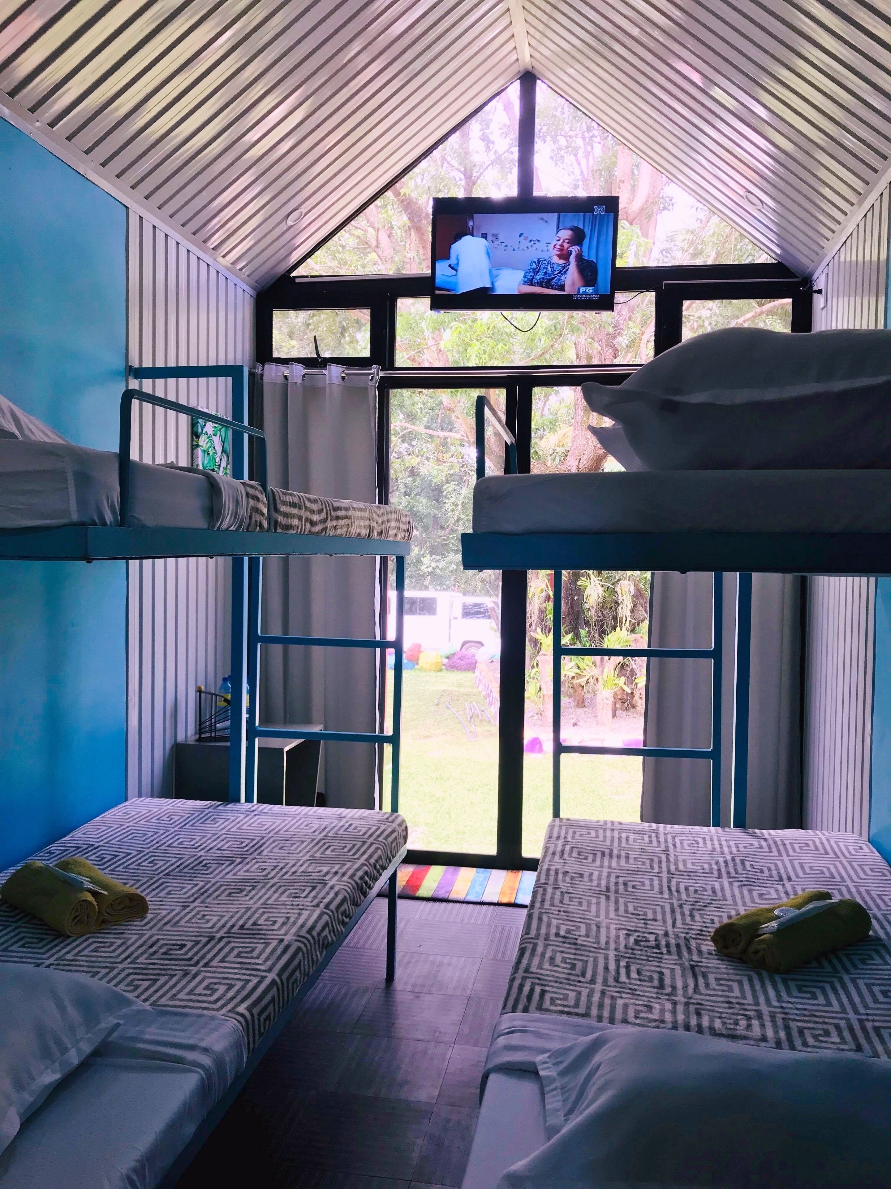 Habitación tipo dormitorio con literas, televisión y vista al exterior.