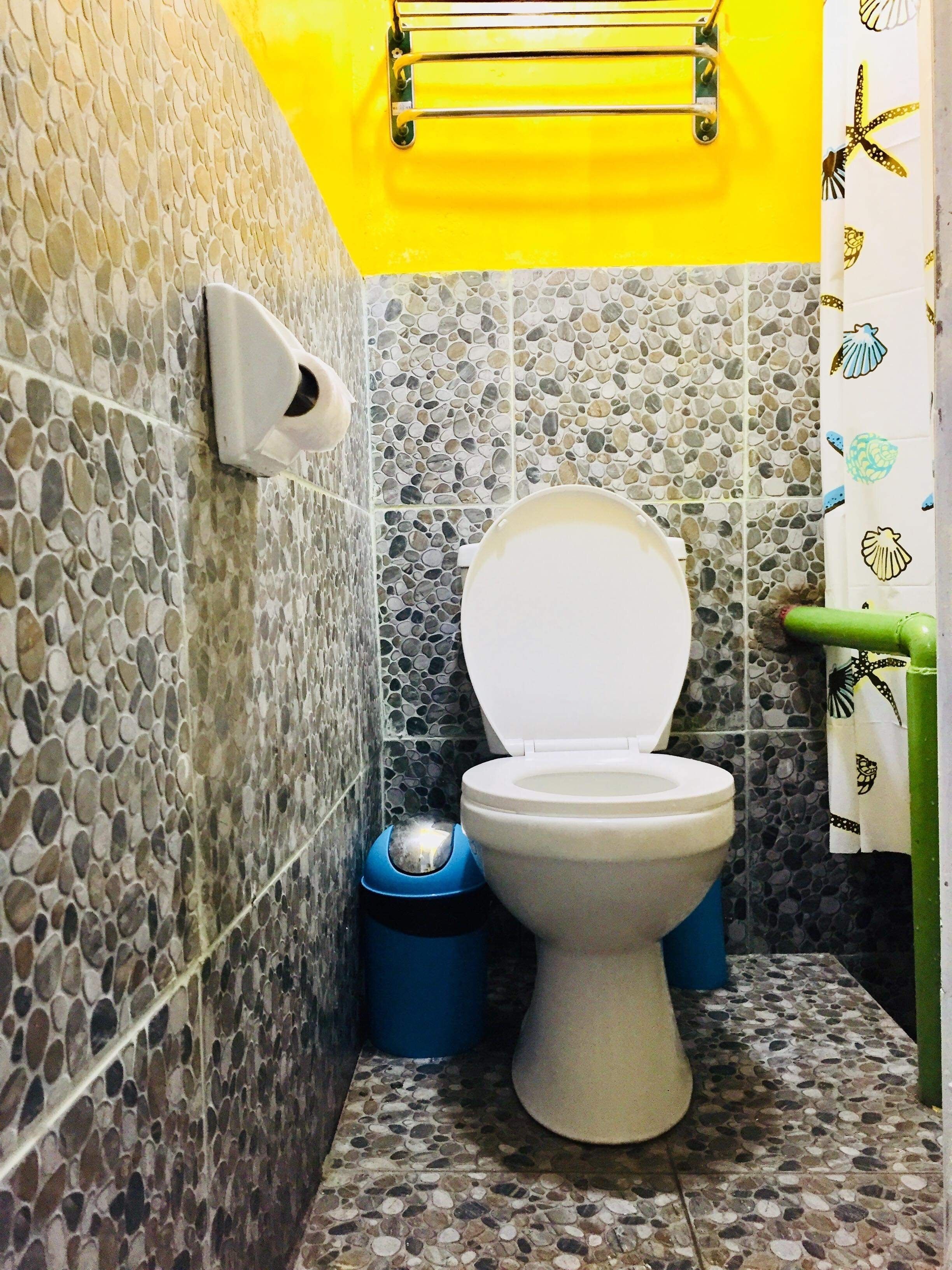 Kylpyhuone, jossa on wc, roskakori ja pyyheteline.