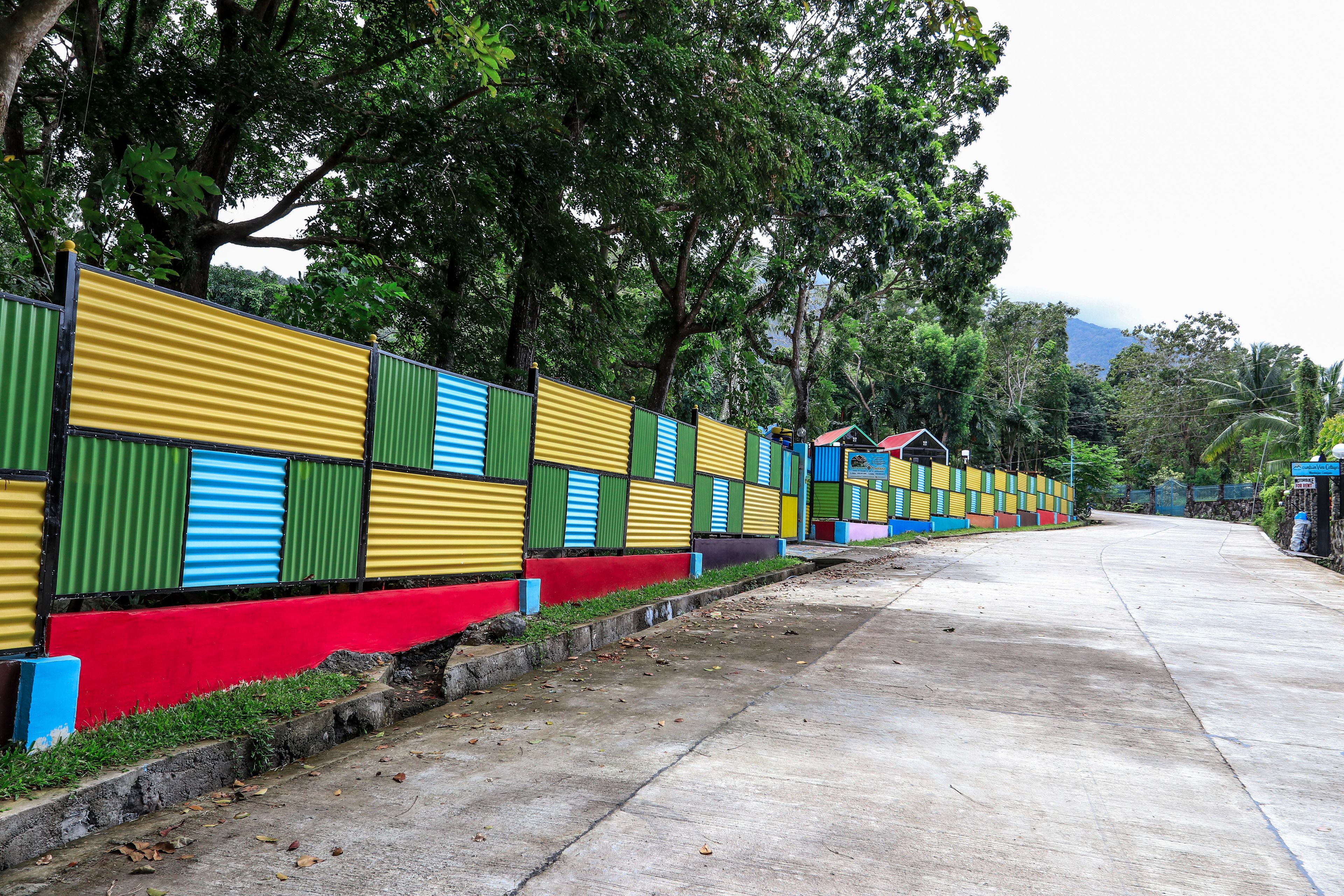 A concrete pathway lined with colorful corrugated metal fences.