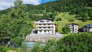 Um hotel com vários andares, varandas, uma parede de pedra e um rio em primeiro plano.