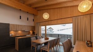 Cozinha moderna com armários de madeira e área de refeições com mesa e cadeiras de madeira.