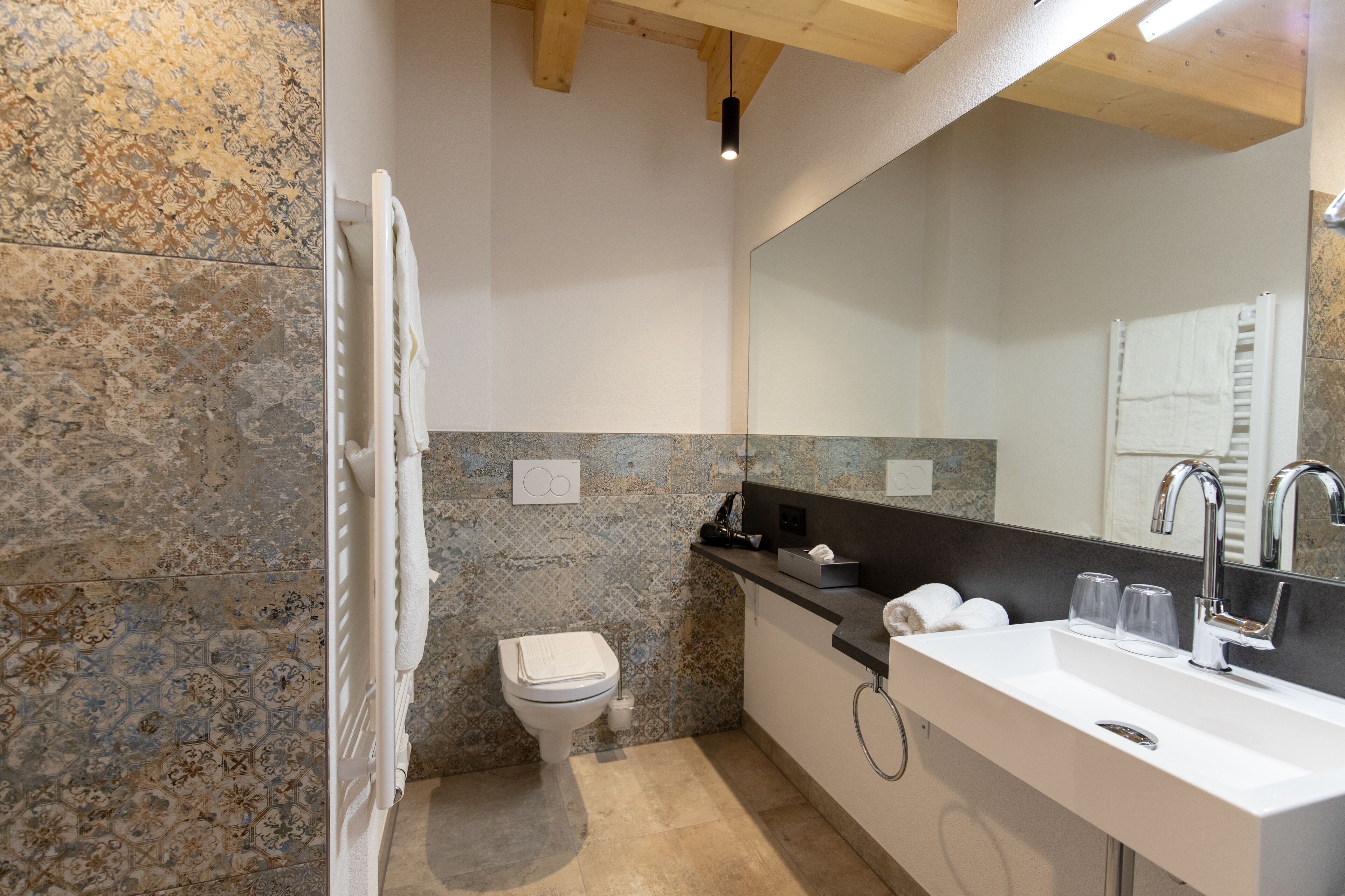 Une salle de bain moderne avec un grand miroir, un lavabo blanc et des toilettes.