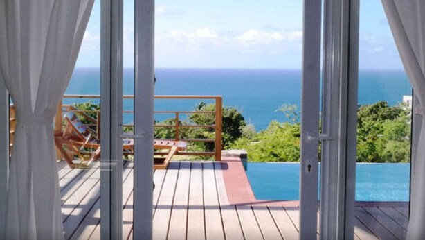 Una terraza de madera con vista al océano y una piscina.