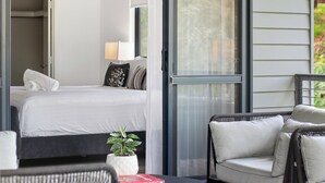 Une chambre d’hôtel moderne, équipée d’un lit, d’une petite table, d’une chaise et d’une plante en pot.