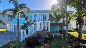 A two-story house with a balcony, surrounded by palm trees and a garden. - The Lazy Tiki - Private Pool (Fort Myers Beach)